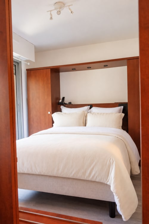 Spacieuse chambre double à l'hôtel La Joya à Cavalaire-sur-Mer avec literie crème, détails bois et balcon vue mer