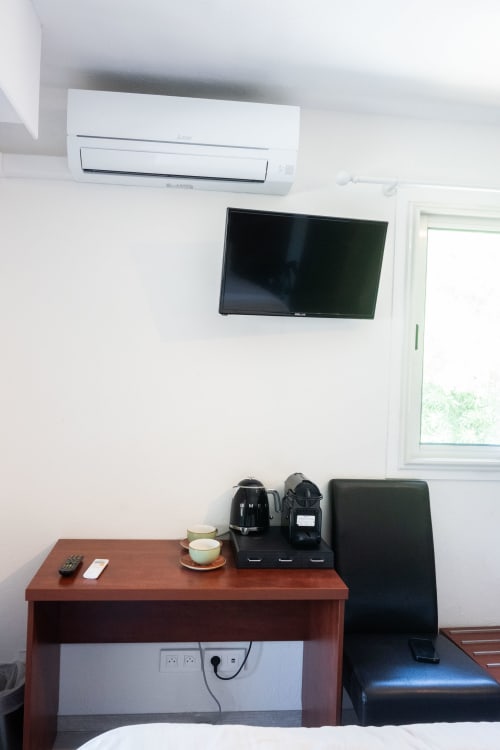 Chambre moderne à La Joya avec climatiseur mural, TV écran plat, bureau en bois avec cafetière et fenêtre donnant sur