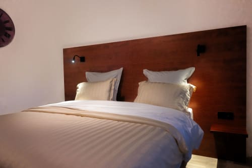 Modern hotel bedroom at La Joya in Cavalaire-sur-Mer with wooden headboard, white linens, and ambient lighting