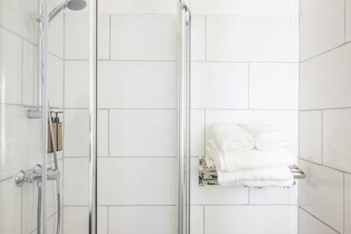 Douche moderne avec carrelage blanc métro, pommeau de douche effet pluie et serviettes blanches à l'hôtel La Joya