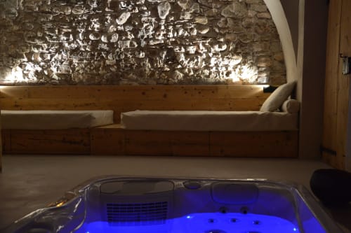 Suite spa lussuosa a Villa Rosati con vasca idromassaggio illuminata e muri in pietra rustica a Sanzeno