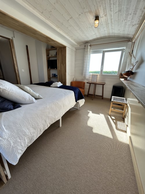 Chambre La Cabine à La Villa Plein Vent avec literie blanche, plafond en bois, baie vitrée vue mer et équipements modernes
