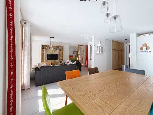 Espace ouvert salle à manger et salon dans l'appartement Le Jardin de Caterina, Montgenèvre, avec table en bois et luminaires suspendus modernes