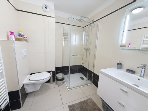 Salle de bain moderne aux carreaux noir et blanc, douche vitrée, vasque blanche, toilettes murales aux Tanières de