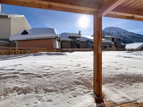 Cour enneigée de Les Tanières de Montgenèvre avec chalets en bois et pics alpins