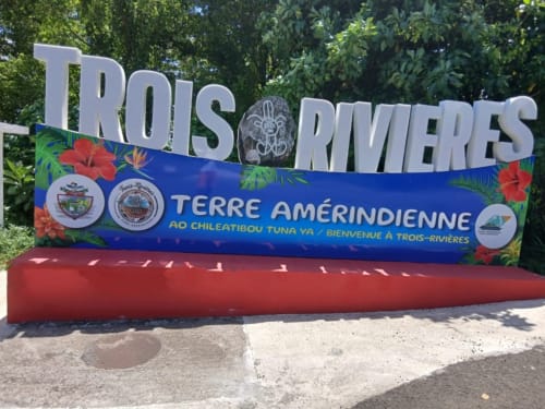 Panneau de bienvenue Trois-Rivières avec fleurs tropicales et socle rouge en Guadeloupe