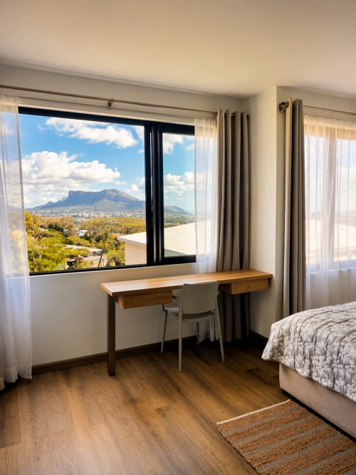 Modern bedroom with wooden desk overlooking Table Mountain, Joubarbe Résidence apartment in Moka, Mauritius