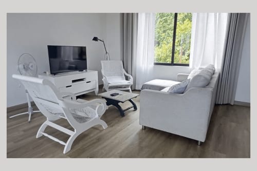 Modern living room at Joubarbe Résidence in Moka with white furniture, flat-screen TV, sofa, and mountain views through large