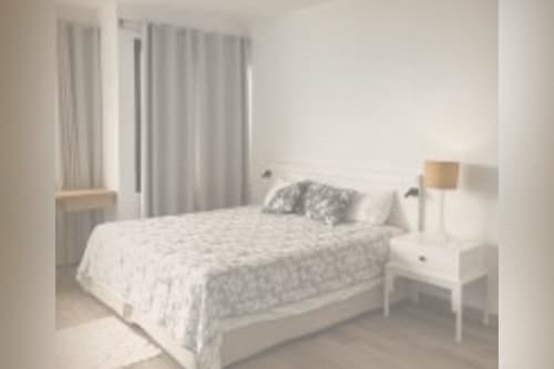 Serene minimalist bedroom with white bedding at Joubarbe Résidence in Moka, Mauritius, featuring mountain views and modern