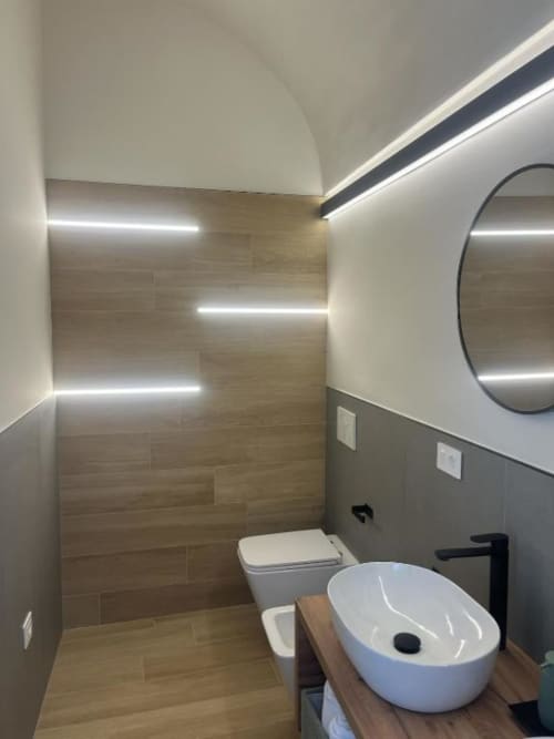 Bagno moderno presso Marelia Suites a Vasto con lavabo bianco, wc, illuminazione LED e pareti rivestite in legno