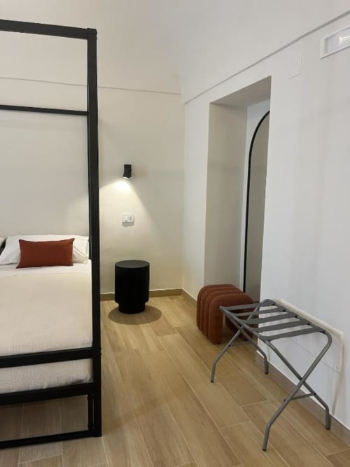 Camera da letto al piano terra di Marelia Suites a Vasto con letto a baldacchino, ottoman nero, portabagagli e arredamento minimalista moderno