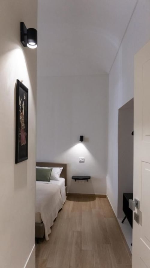 Camera matrimoniale moderna presso Marelia Suites a Vasto con pareti bianche, pavimento in legno e illuminazione d'atmosfera