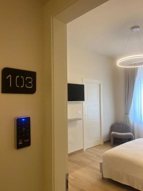 Camera 103 moderna di Marelia Suites a Vasto con letto, pannello smart, TV e lampada a sospensione rotonda