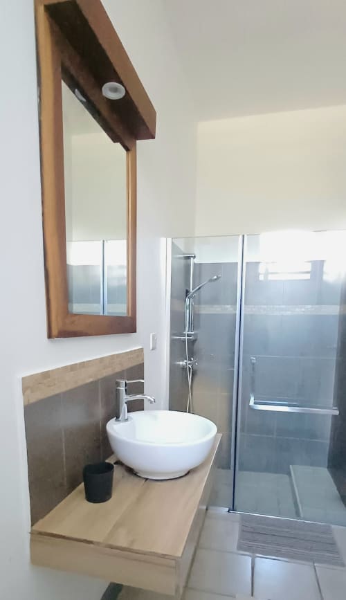 Modern bathroom at Joubarbe Résidence Moka with vessel sink, glass shower enclosure, and wooden vanity