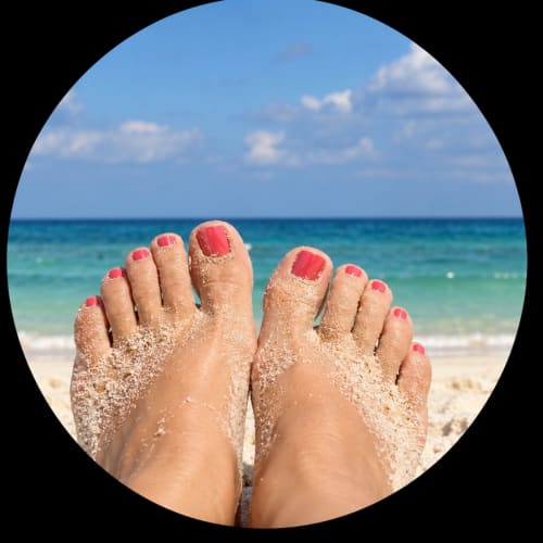 Sandy feet with pink nail polish overlooking turquoise ocean at Breizh beachfront apartment in Guilvinec, France