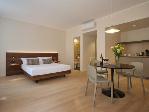 Flavia Junior Suite Deluxe di Portica Homes Assisi con letto in legno, tavolo da pranzo, angolo cottura e comfort moderni