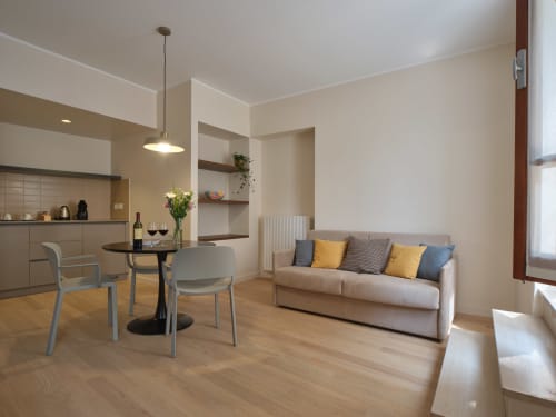 Flavia Junior Suite Deluxe a Portica Homes Assisi con living open space, divano beige, zona pranzo e angolo cottura