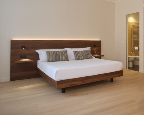 Camera moderna con letto in legno scuro e biancheria bianca presso la Junior Suite Deluxe di Portica Homes ad Assisi, Italia