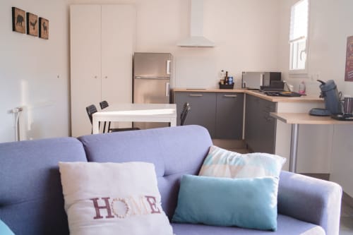 Modern studio apartment at Résidence des Sables with blue sofa, open-plan kitchen, dining area, and work desk in Mably,