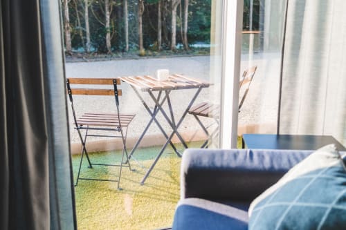 Sunny patio at Résidence des Sables in Mably with folding chairs, small table, and forest view