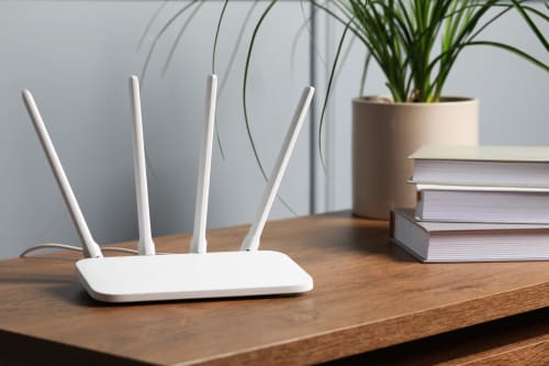 White Wi-Fi router with four antennas on wooden desk at Résidence des Sables, Mably