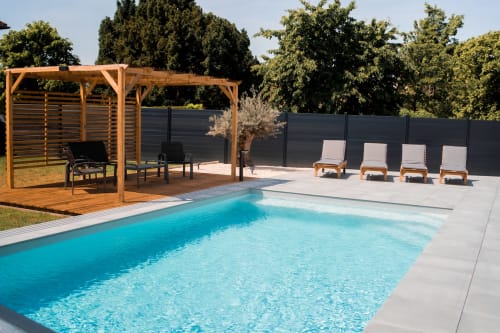 Résidence des Sables pool area with wooden pergola, lounge chairs, and dark privacy fence in Mably