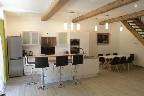 Moderne Küche und Esszimmer im Domaine Le Piboul mit weißen Schränken, Kochinsel und sichtbaren Holzbalken