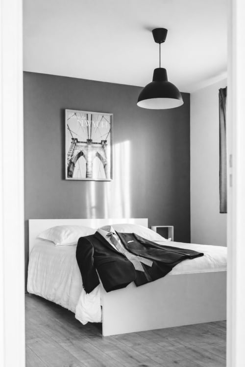 Chambre moderne à la Résidence des Sables Mably : lit blanc, mur d'accent gris, applique suspendue noire et gravure architecturale