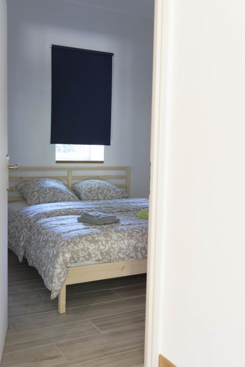 Schlafzimmer im Cottage La Grange im Domaine Le Piboul mit Holzbett, gemusterter Bettwäsche und Verdunkelungsrollo