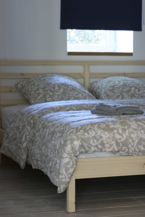 Gemütliches Schlafzimmer im Domaine Le Piboul mit Holzbett, gemusterter Bettwäsche und Gartenblick im Cottage La Grange