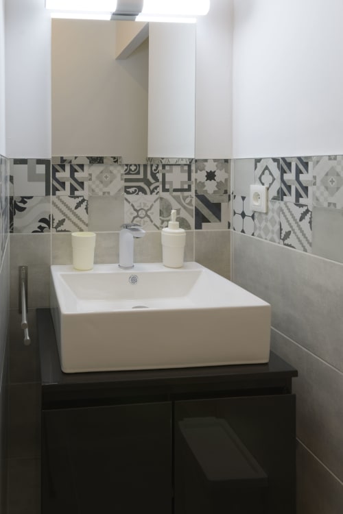Modernes Badezimmer mit weißem rechteckigem Waschbecken, gemustertem Fliesenspritzschutz und Spiegel im Ferienhaus Domaine Le Piboul