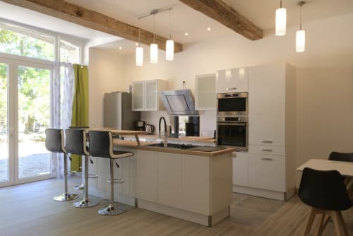 Moderne Cottage-Küche im Domaine Le Piboul mit weißen Schränken, Holzbalken, Pendelleuchten und Barplätzen mit Aussicht
