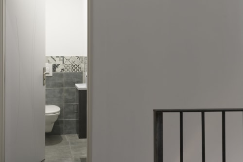 Modernes Badezimmer im Ferienhaus Domaine Le Piboul mit grauen Fliesen, Toilette, Waschbecken und dekorativen Fliesenakzenten
