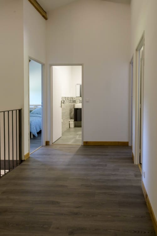 Flur im Ferienhaus La Grange auf dem Domaine Le Piboul, Fontcouverte, mit dunklem Holzboden und weißen Türen, die zum Schlafzimmer führen und