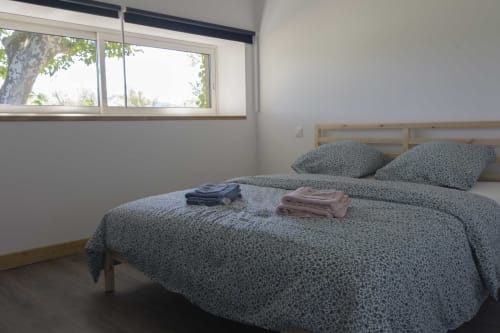 Helles Schlafzimmer im Cottage Domaine Le Piboul mit Queensize-Bett, Gartenblick und gefalteter Bettwäsche