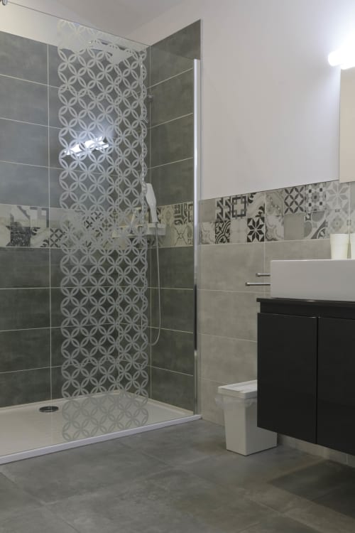 Modernes Badezimmer mit gemusterter begehbarer Dusche, dunklem Waschtisch und geometrischen Fliesenakzenten im Ferienhaus Domaine Le Piboul