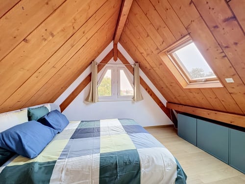 Chambre spacieuse sous les toits avec poutres en bois, lit queen-size avec literie bleue, lucarne et vue sur la rivière à A L'ill Apart