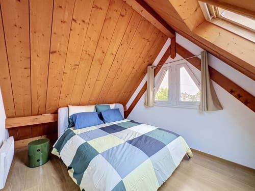 Chambre cosy sous les toits à L'Ill Apart : plafond en bois, literie patchwork colorée, vue sur la rivière à La Wantzenau