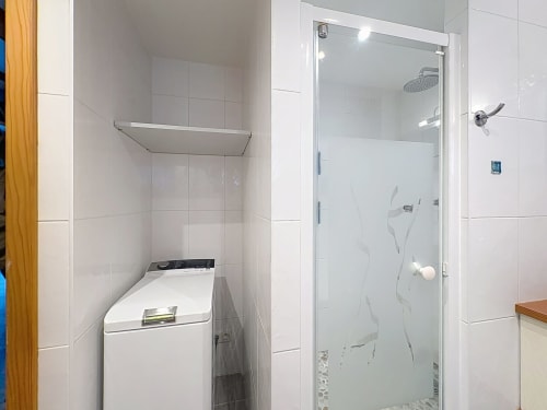 Salle de bain moderne avec douche à l'italienne, lave-linge et murs carrelés blancs à l'A L'ill Apart à La Wantzenau