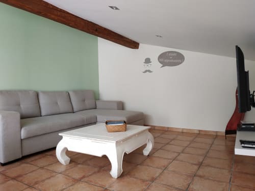 Wohnzimmer eines Landhauses im Domaine Le Piboul mit grauem Sofa, weißem Couchtisch, Terrakotta-Fliesen und Wanddekoration