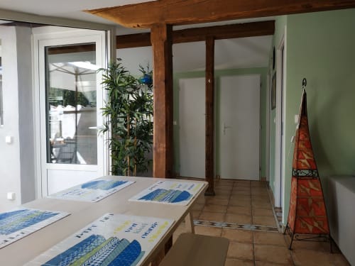 Helles Cottage-Interieur im Domaine Le Piboul mit Holzbalken, Essbereich, Türen mit Gartenblick und grünen Akzentwänden