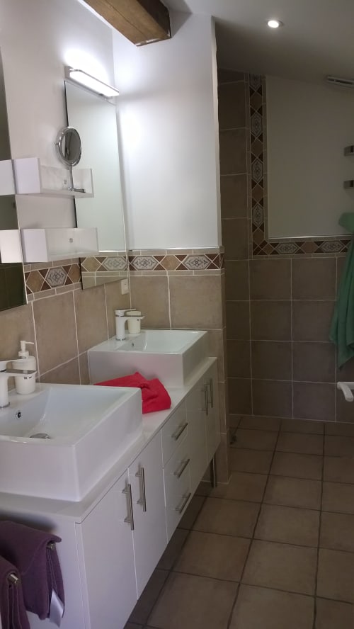 Modernes Badezimmer mit Doppelwaschbecken, gekacheltem Duschbereich und dekorativem Spiegel im Ferienhaus Domaine Le Piboul in Fontcouverte