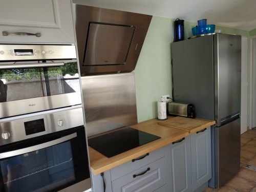 Moderne Küche mit Edelstahlgeräten, Holzarbeitsplatte und weißen Schränken im Cottage Domaine Le Piboul