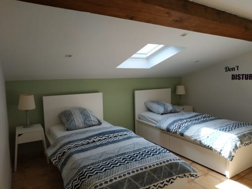 Doppelzimmer im Gästehaus Les Cuves im Domaine Le Piboul mit grüner Akzentwand und Dachfenster