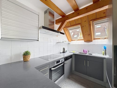 Cuisine moderne de l'appartement A L'ill Apart, La Wantzenau, avec poutres en bois, électroménagers inox et fenêtres toit
