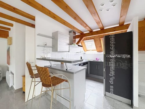 Cuisine moderne de l'appartement avec poutres en bois, îlot de repas et réfrigérateur noir à A L'ill Apart, La Wantzenau