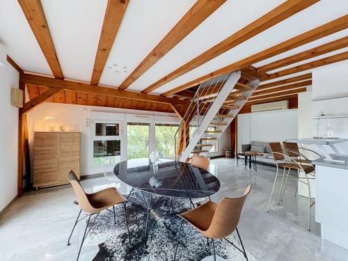 Appartement moderne au bord de l'eau à La Wantzenau avec poutres en bois apparentes, table à manger noire et séjour ouvert