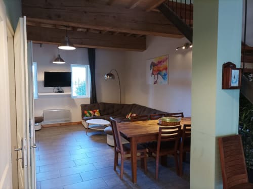 Geräumiges Wohnzimmer mit Esstisch, braunem Sofa, Fernseher und sichtbaren Holzbalken im Domaine Le Piboul