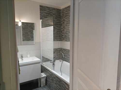 Modernes Badezimmer im Domaine Le Piboul mit weißem Waschbecken, Badewanne, gestreiften Fliesen und gläserner Duschkabine