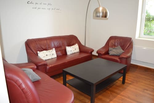 Gemütliches Wohnzimmer mit roten Ledersofas, schwarzem Couchtisch und Bogenleuchte im Cottage Le Régisseur auf Domaine Le Piboul